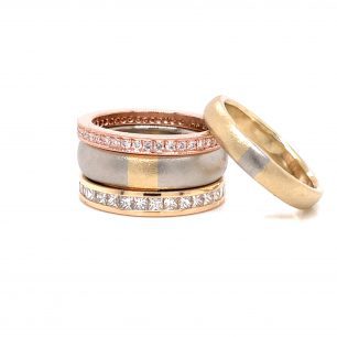 Ring with one placed above the other. The two bands have alternating designs of silver and yellow. Other two ring is rose gold design adorned with diamonds. The object is set on white background.