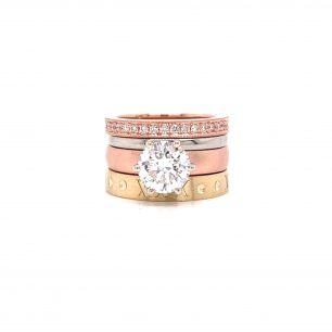 Ring has a plated band that is tri-colored with yellow, silver, and rose gold, one rose gold band adorned with diamonds. The ring has round diamond as focal point. The object is set on white background.