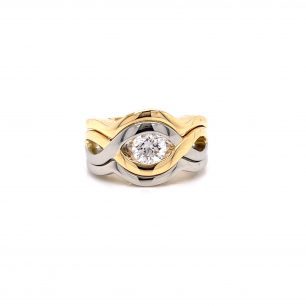Ring with a distinctive band design. The band is composed of both silver and yellow gold, and it features a round diamond as centerpiece. The object is set on white background.