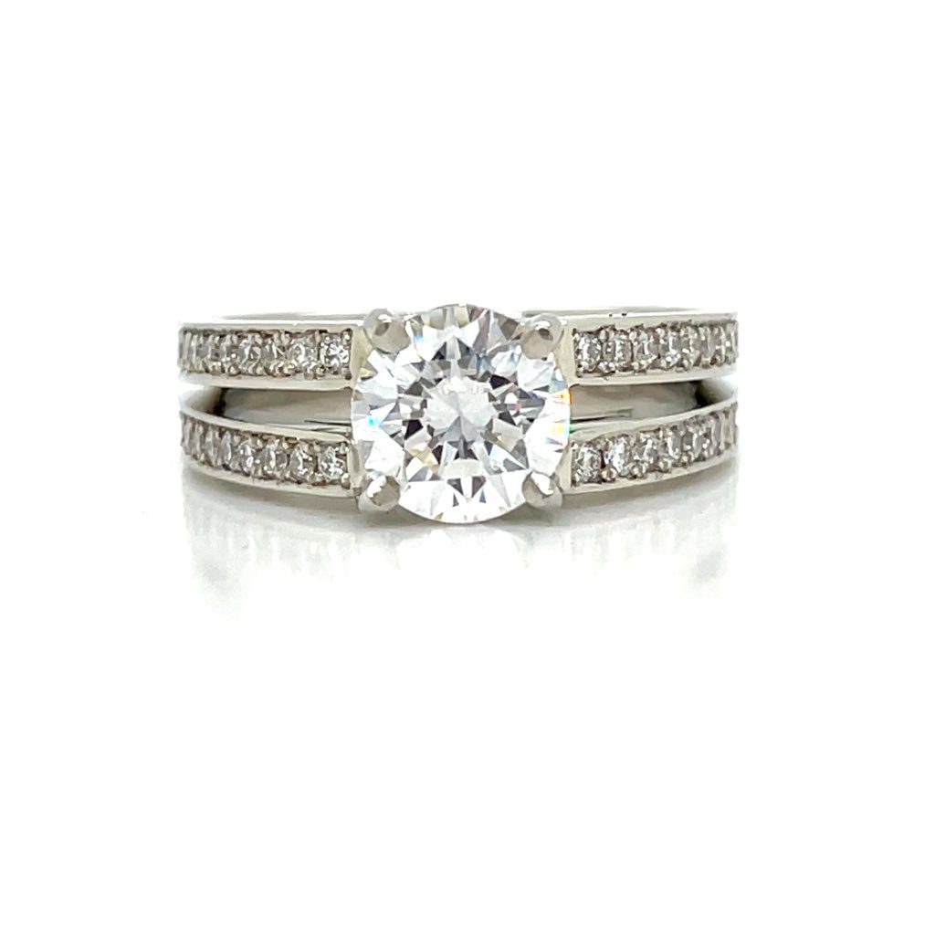 White diamond ring with a band that has a split shank design, and it is mounted with a round diamond. The object is set on white background.